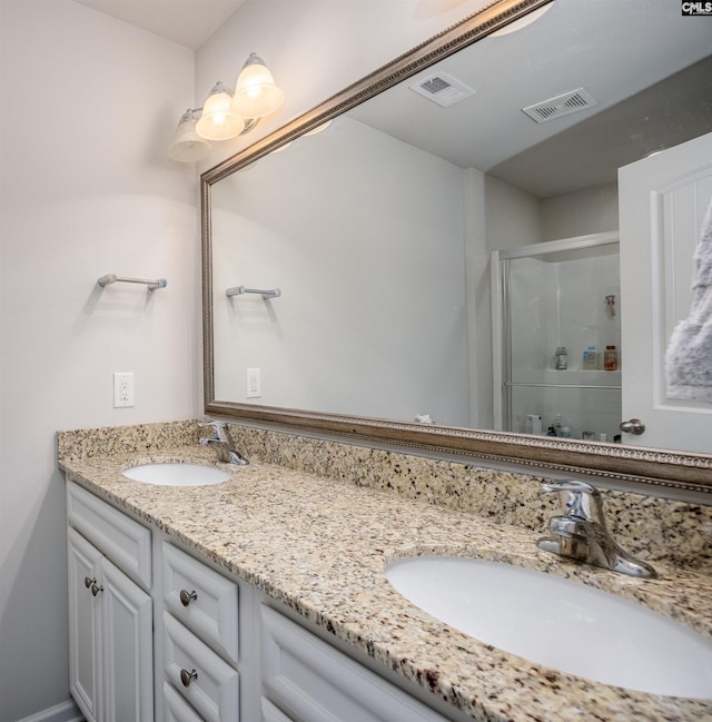 bathroom featuring double vanity, a shower stall, visible vents, and a sink