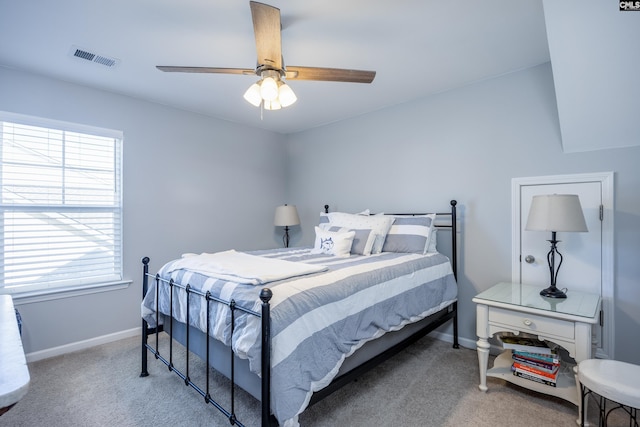 carpeted bedroom featuring a ceiling fan, visible vents, and baseboards