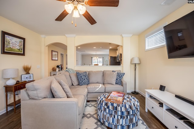 living room featuring arched walkways, plenty of natural light, and dark wood finished floors