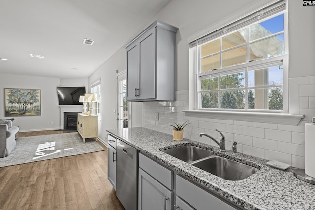 kitchen featuring visible vents, dishwasher, open floor plan, gray cabinets, and a sink