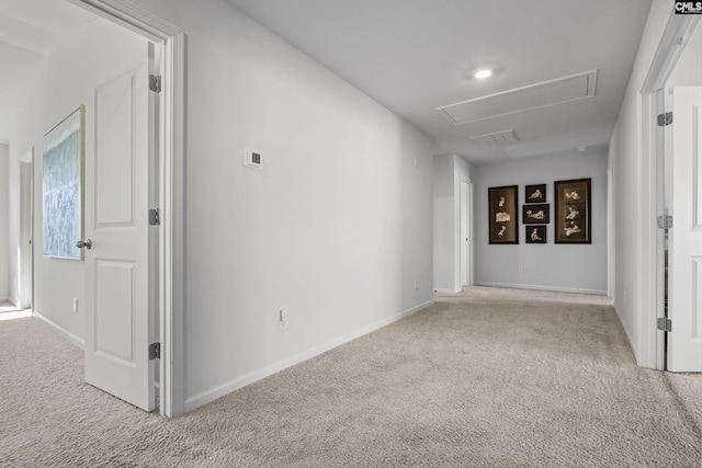 corridor featuring attic access, carpet, visible vents, and baseboards