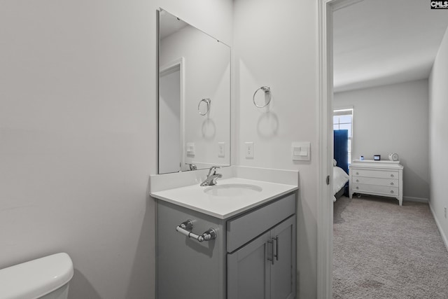 half bath with toilet, baseboards, and vanity