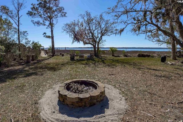 view of yard with an outdoor fire pit and a water view