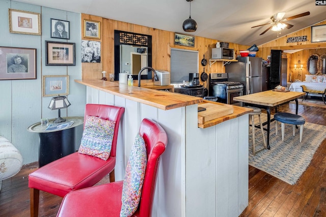 kitchen featuring appliances with stainless steel finishes, vaulted ceiling, wooden counters, and hardwood / wood-style floors