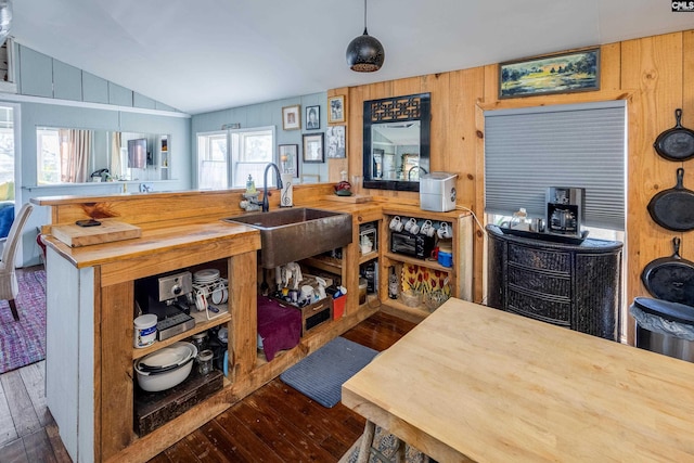 kitchen with hardwood / wood-style flooring, butcher block counters, wood walls, a sink, and vaulted ceiling