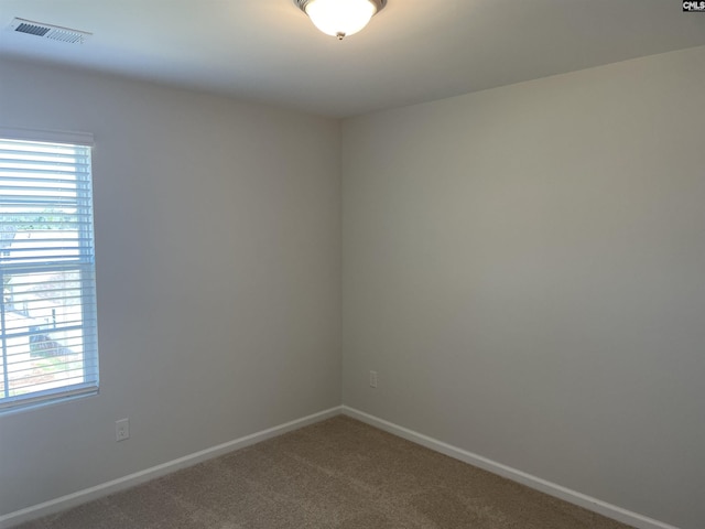 unfurnished room featuring carpet floors, visible vents, and baseboards