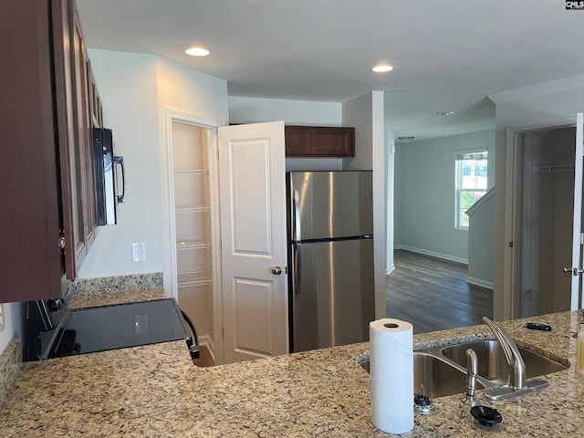 kitchen with black appliances, recessed lighting, and light stone countertops