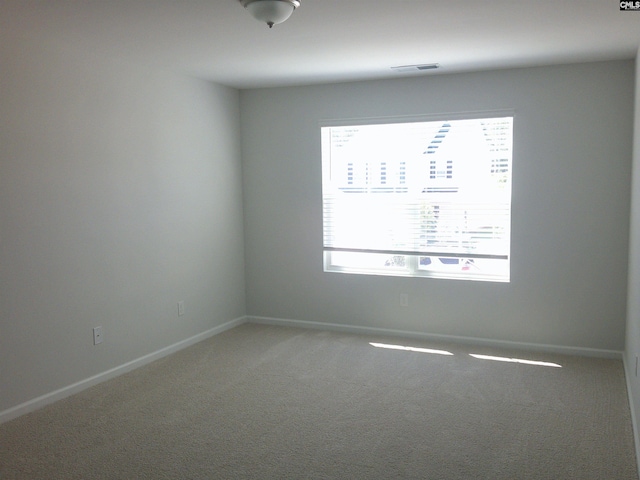 empty room featuring carpet, plenty of natural light, visible vents, and baseboards