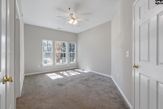 spare room featuring carpet floors, ceiling fan, visible vents, and baseboards