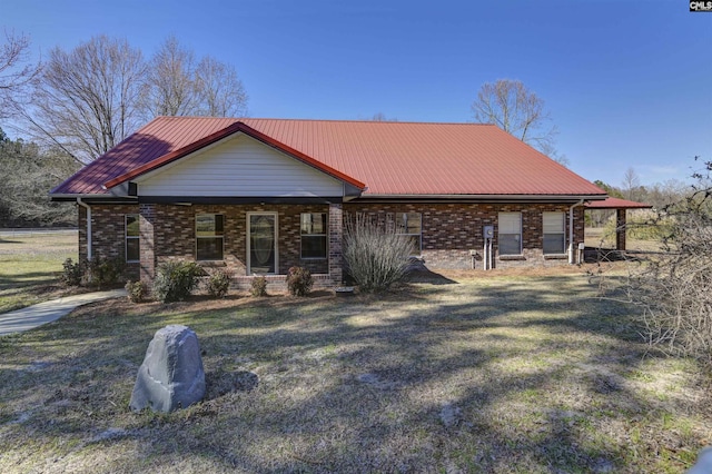 view of front of home with metal roof, brick siding, and a front yard