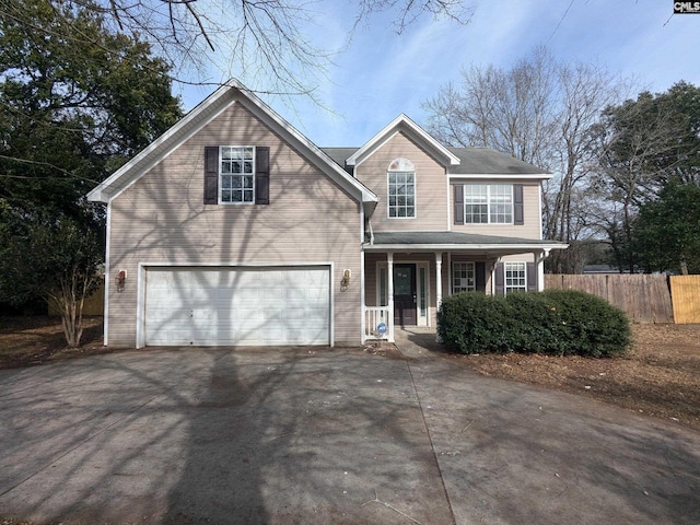 traditional home featuring driveway, an attached garage, fence, and a porch