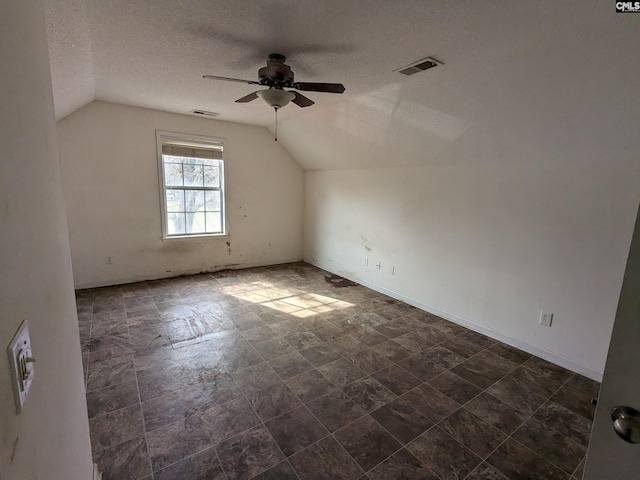 additional living space with a textured ceiling, lofted ceiling, visible vents, and a ceiling fan