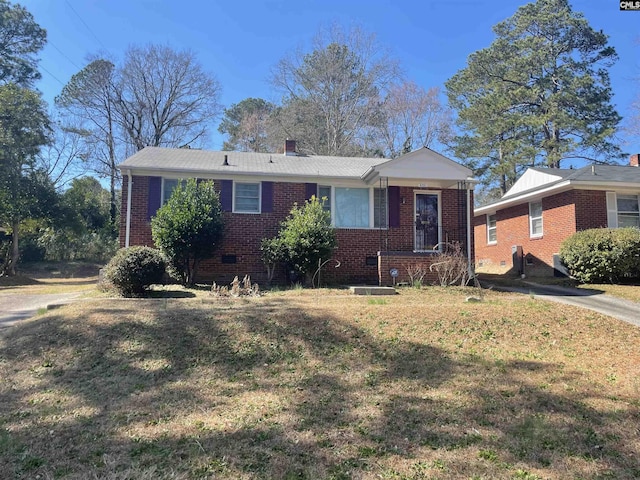 view of front of house featuring a front yard, crawl space, brick siding, and a chimney