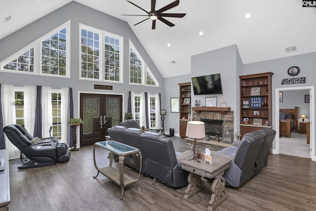 living area with french doors, a fireplace, a wealth of natural light, ceiling fan, and wood finished floors