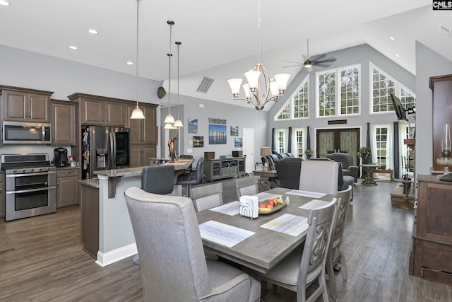 dining area with high vaulted ceiling, visible vents, dark wood finished floors, and ceiling fan with notable chandelier