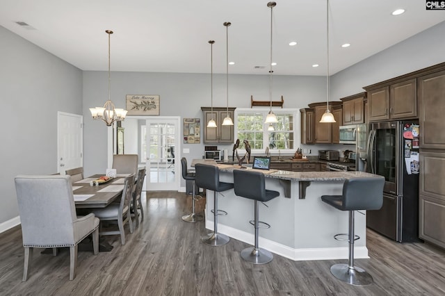 kitchen featuring visible vents, appliances with stainless steel finishes, a kitchen breakfast bar, dark wood-style flooring, and a center island