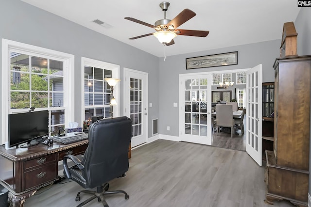 home office featuring french doors, visible vents, wood finished floors, baseboards, and ceiling fan with notable chandelier