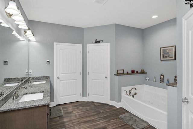 full bathroom featuring a garden tub, a sink, and wood finished floors