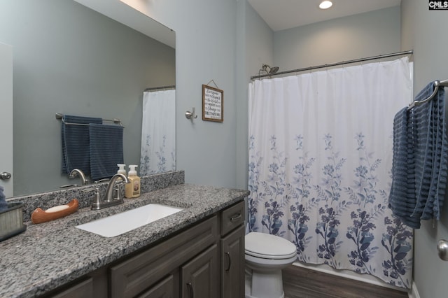 bathroom with toilet, a shower with curtain, wood finished floors, and vanity