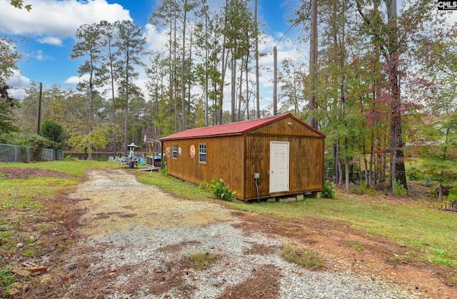 view of outdoor structure with an outbuilding, driveway, and fence