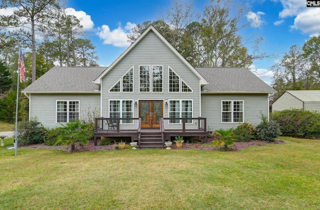 rear view of property featuring a shingled roof, french doors, a lawn, and a deck