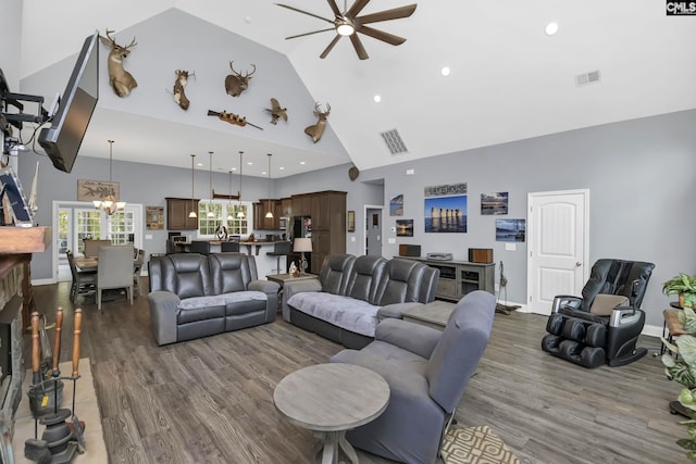 living room featuring dark wood-style floors, ceiling fan with notable chandelier, and visible vents