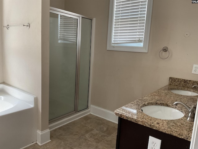 full bath with a bath, a shower stall, baseboards, and a sink