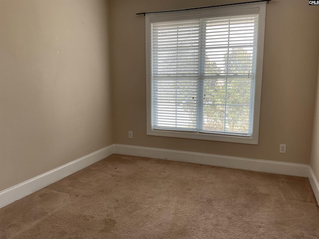 spare room with light carpet and baseboards