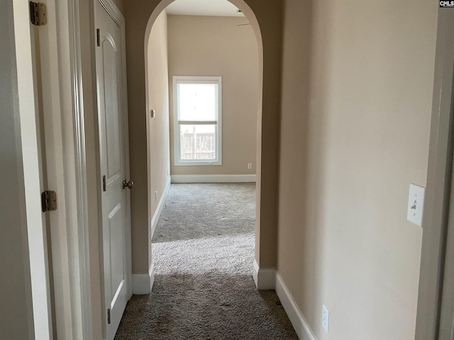 hall featuring carpet, arched walkways, and baseboards