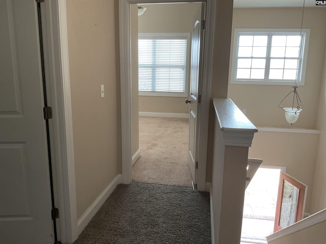 hallway with carpet flooring, an upstairs landing, and baseboards