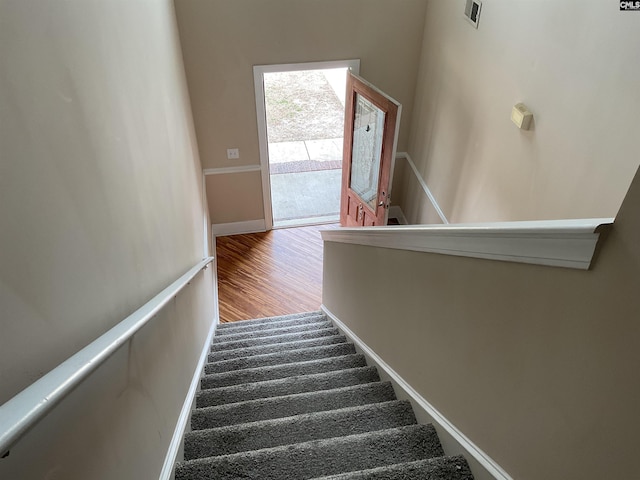 stairway with visible vents, baseboards, and wood finished floors