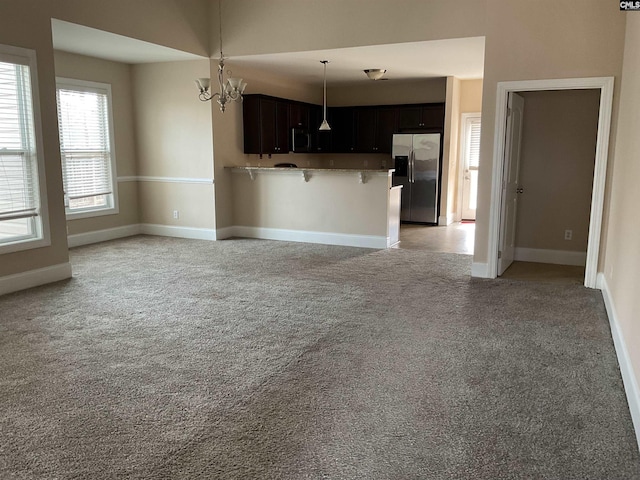 kitchen with open floor plan, light carpet, stainless steel fridge, and a kitchen breakfast bar