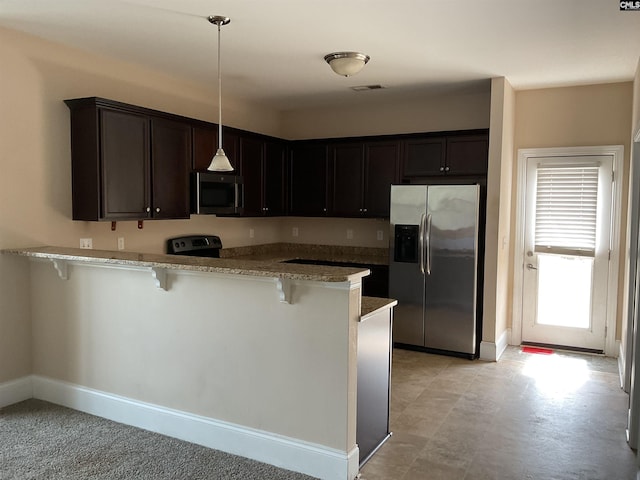 kitchen featuring appliances with stainless steel finishes, light stone counters, a breakfast bar area, a peninsula, and pendant lighting