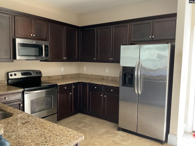 kitchen featuring light stone countertops, stainless steel appliances, and dark brown cabinets