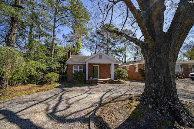 view of front of house with a porch, crawl space, brick siding, and a chimney