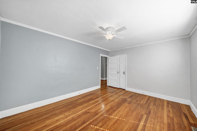 empty room featuring ceiling fan, baseboards, wood finished floors, and ornamental molding