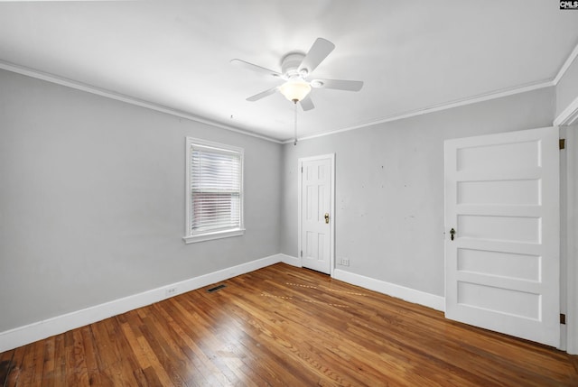 unfurnished room featuring baseboards, visible vents, wood-type flooring, and crown molding