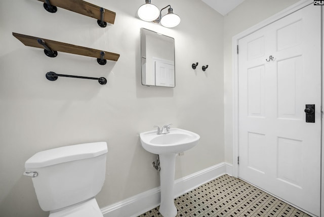 half bath with a sink, toilet, and baseboards