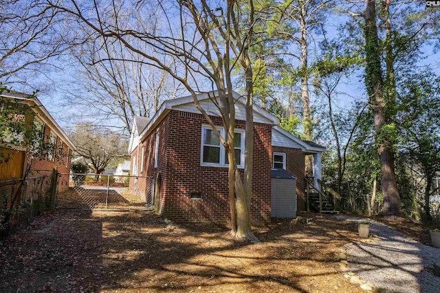 view of side of property with crawl space, a gate, fence, and brick siding