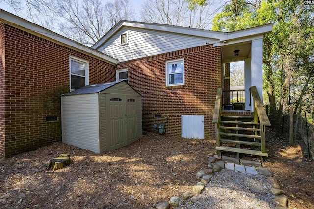 back of property featuring an outbuilding, crawl space, brick siding, and a shed