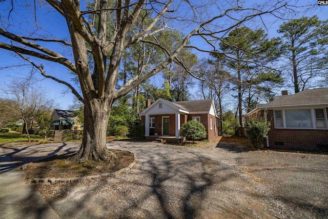 view of front facade featuring aphalt driveway, crawl space, and brick siding