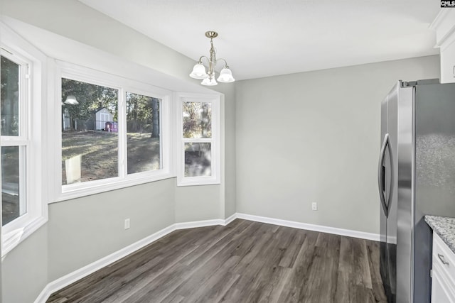 unfurnished dining area with baseboards, dark wood finished floors, and a notable chandelier