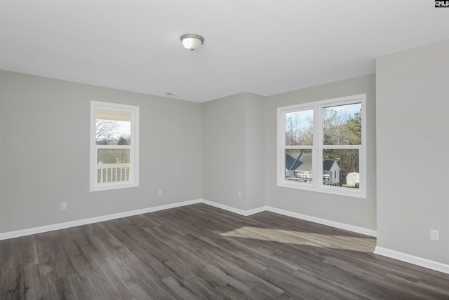 spare room featuring dark wood-style floors and baseboards