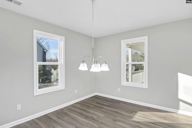 empty room featuring baseboards, visible vents, and wood finished floors