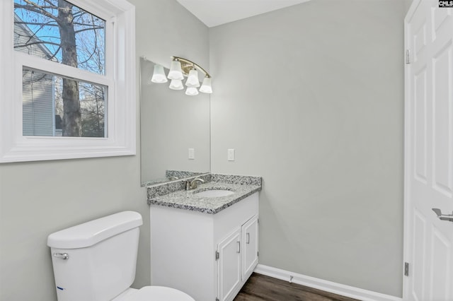 bathroom with wood finished floors, vanity, toilet, and baseboards