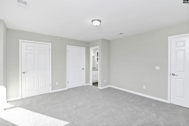 unfurnished bedroom with carpet floors, visible vents, connected bathroom, and baseboards