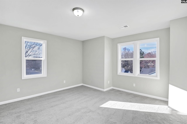 empty room featuring carpet floors, visible vents, and baseboards