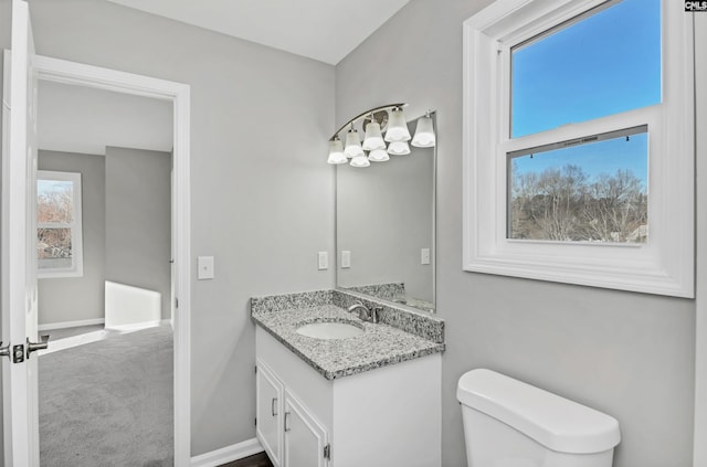 half bath with vanity, toilet, and baseboards