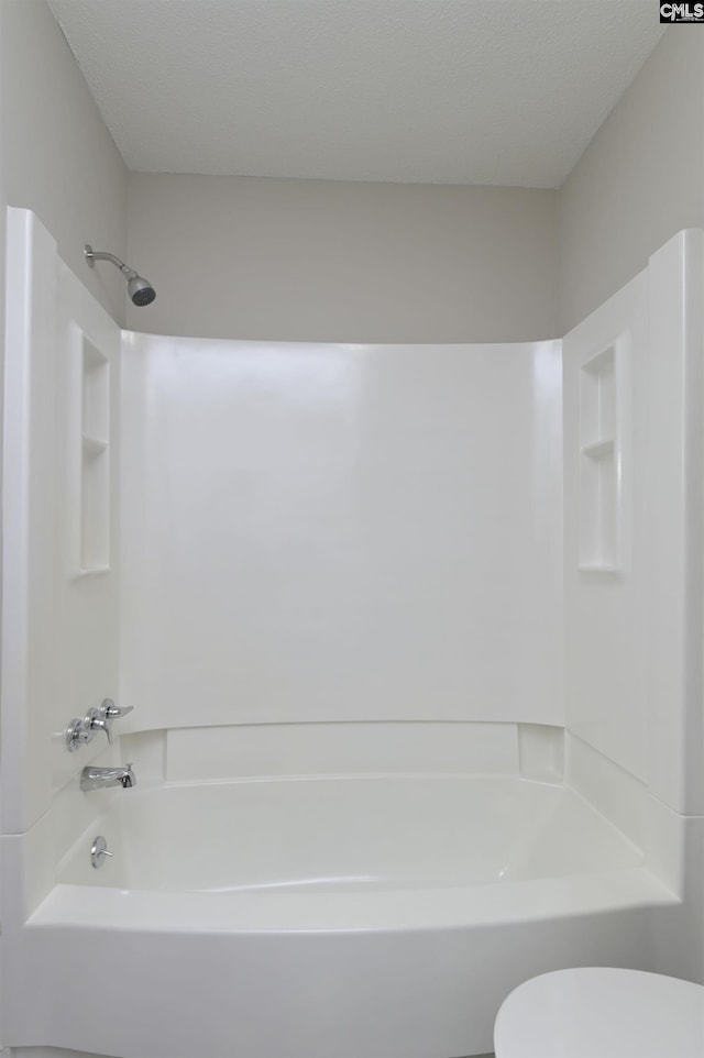 bathroom featuring  shower combination, a textured ceiling, and toilet