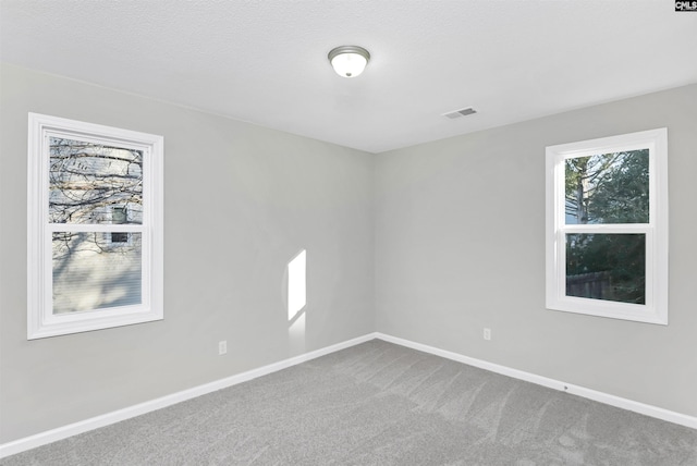 carpeted spare room with baseboards and visible vents